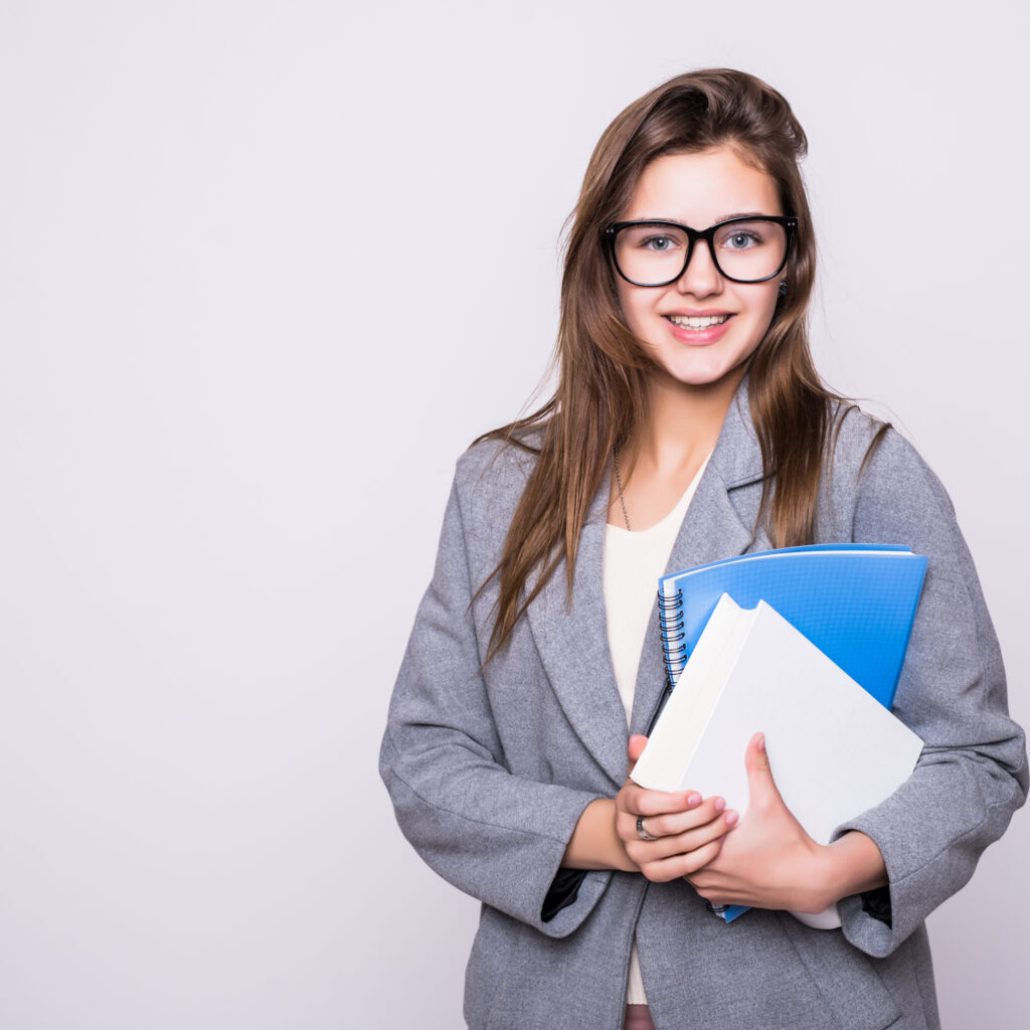 pretty and young student with big funny glasses near some books smiling in camera